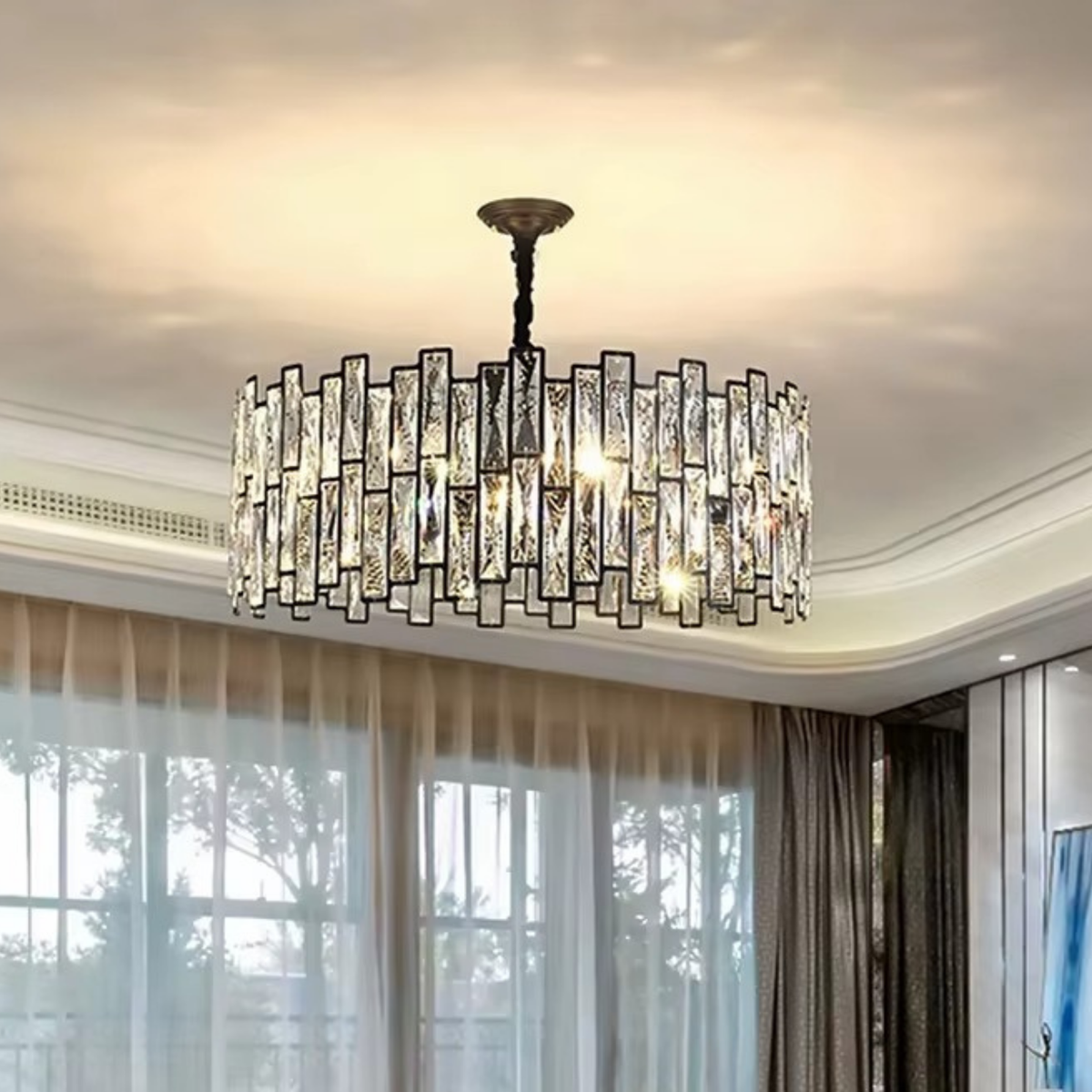 Large round crystal chandelier hanging in a bright luxury living room with floor-to-ceiling windows - statement crystal pendant light - Litora