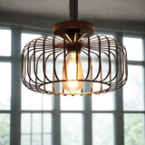 Black round wire cage ceiling light with glowing Edison bulb installed in front of large factory windows - industrial semi-flush light - Litora