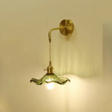 Vintage ribbed green glass wall sconce with brass arm lit on warm wall - Litora
